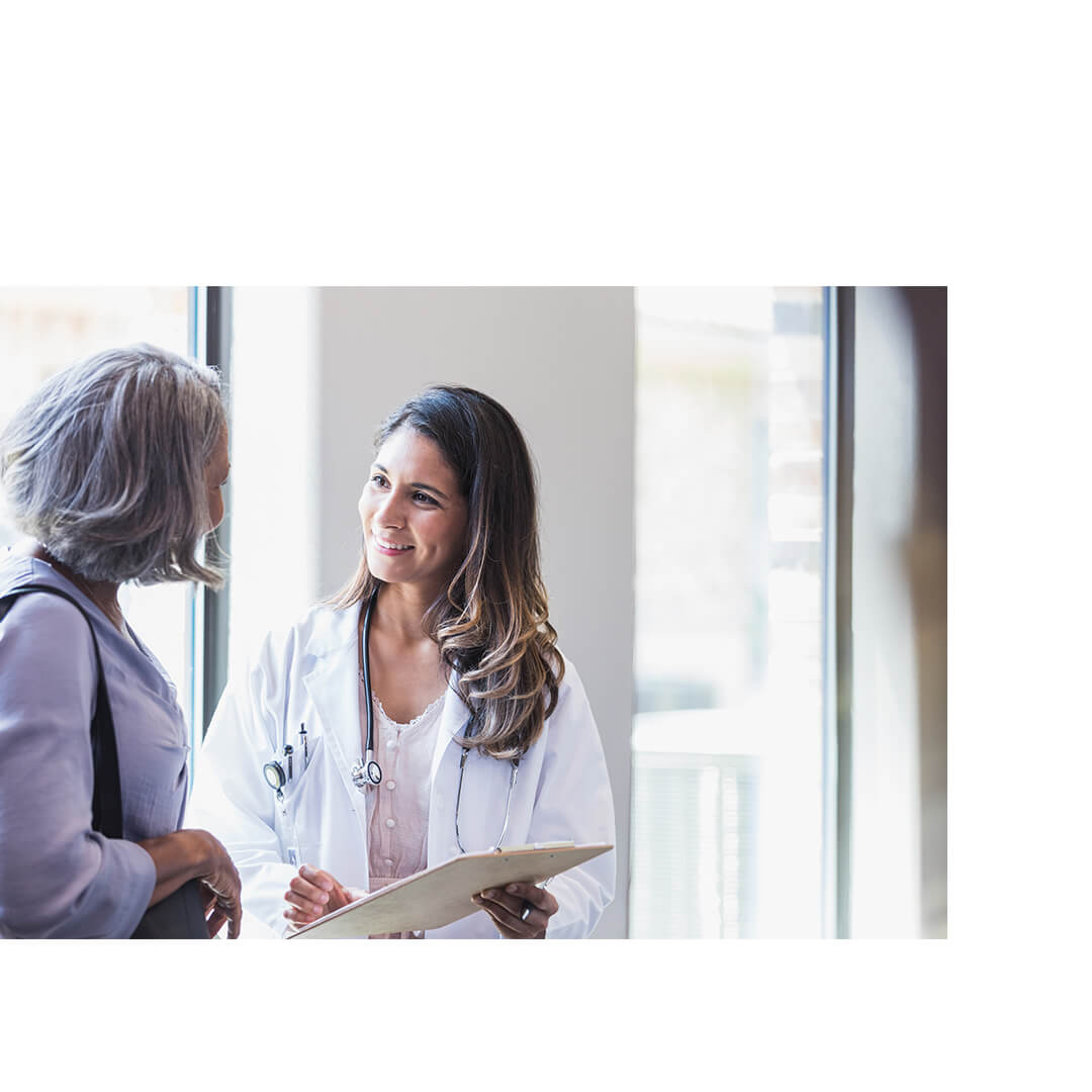 A nurse and an adult patient smiling and reviewing information on a clipboard