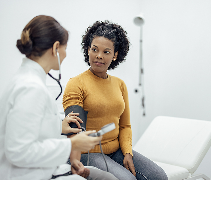 A healthcare provider measures a patient’s blood pressure in a bright clinic room, symbolizing cancer care locations
