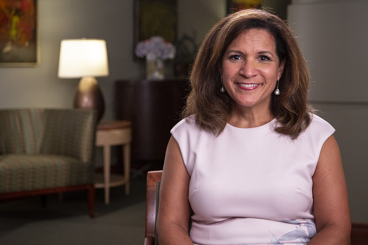 Ann Marie Wallace, smiling in a softly lit office setting, offers a warm and hopeful presence as a cancer patient advocate